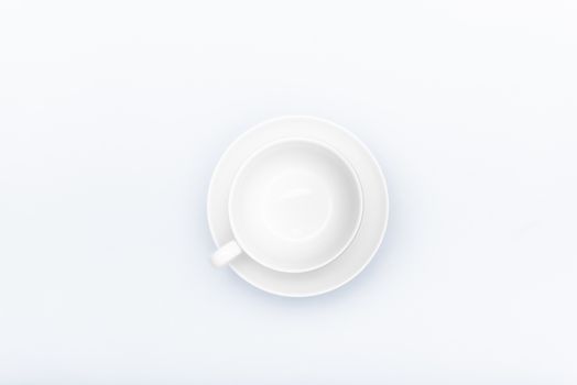 white porcelain cup on a saucer on a white background with copyspace