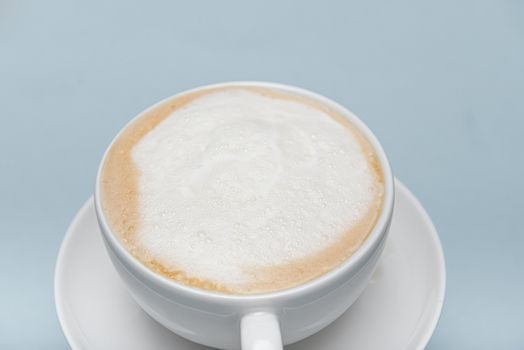 part of white cappuccino cup isolated on a blue background with copyspace