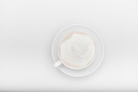 white cup with saucer and cappuccino on a white background with copyspace