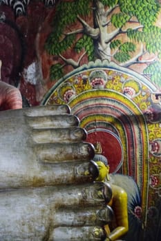 Dambulla, Sri Lanka, Aug 2015: Feet of the giant Buddha in the Dambulla Cave temple under a mural depicting the tree of life