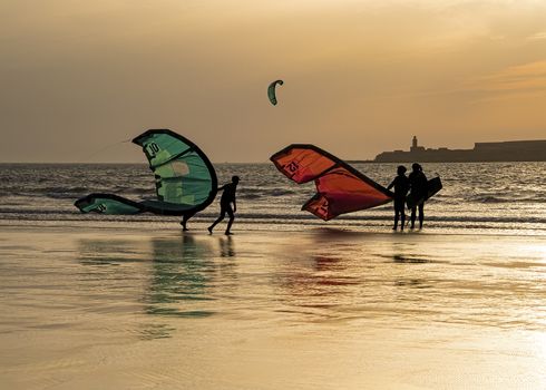 Essaouria, Morocco - September 2017: 
Kite surfers returning from the sea as the sun sets