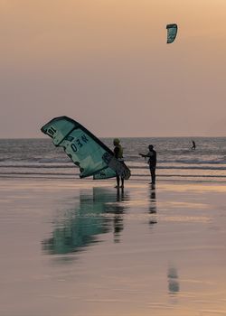 Essaouria, Morocco - September 2017: 
Kite surfers returning from the sea as the sun sets