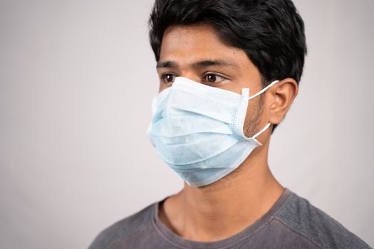 Young man properly covered nose and mouth with face mask - Awareness and safety concept to ware mask properly, to protect from coronavirus or covid-19 crisis on isolated background