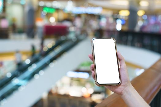 Mockup, hands holding blank white screen mobile phone in blurred department store, digital payment concept