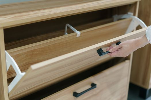 Woman opening wooden shoes storage cabinet for keep her shoes.