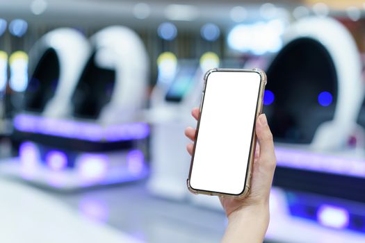 Mockup, hands holding blank white screen mobile phone in blurred game center, digital payment concept