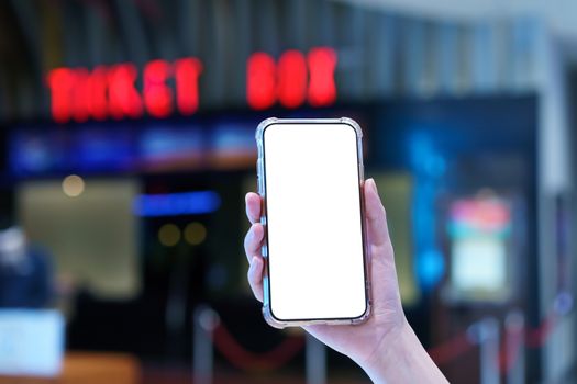 Mockup, hands holding blank white screen mobile phone in blurred cinema, digital payment concept