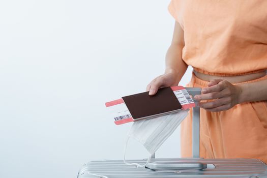 Woman hand holding face mask luggage passport and boarding pass, new normal travel concept.(Fake barcode)