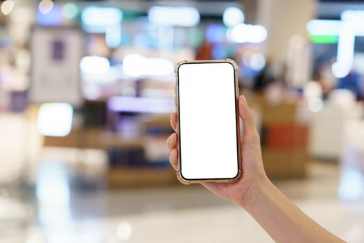 Mockup, hands holding blank white screen mobile phone in blurred department store, digital payment concept