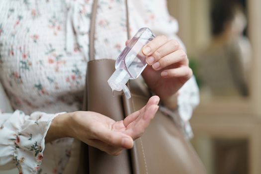 Woman using hand sanitizer spray from her hand bag, prevention of coronavirus.
