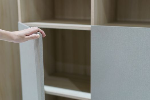 Female hand open the cupboard doors, open brown and white cabinet.