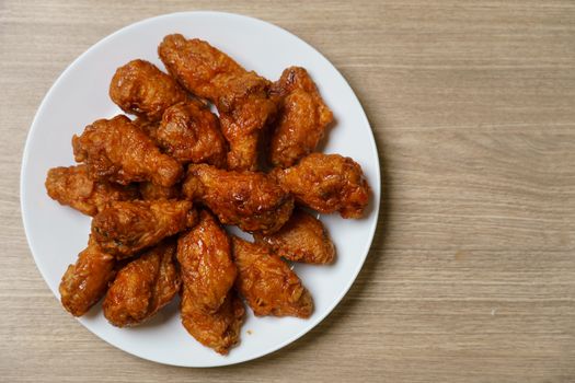 Plate of spicy deep fried chicken wings, Korean food style on wooden table.