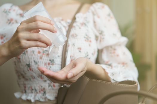 Woman using hand sanitizer spray from her hand bag, prevention of coronavirus.