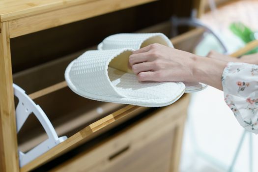 Woman opening wooden shoes storage cabinet for keep her shoes.