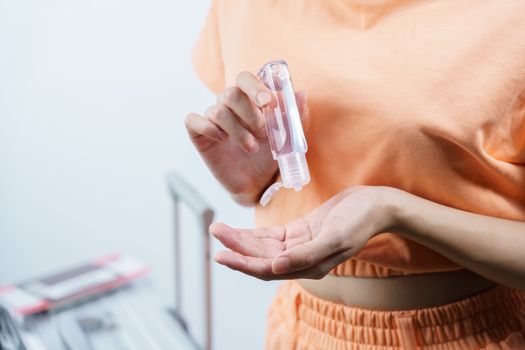 Woman using alcohol gel or sanitizer gel clean her hand, face mask luggage passport and boarding pass, new normal travel concept.