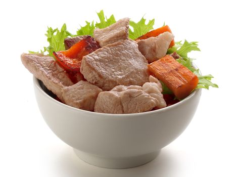 Pieces of roasted pork with fresh lettuce and fried vegetables in the bowl