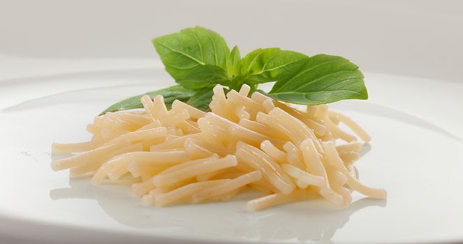Isolated boiled vermicelli with fresh green basil on the white plate