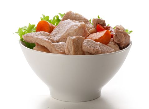 Pieces of roasted pork with fresh lettuce and fried vegetables in the bowl