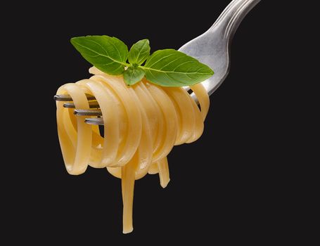 Pasta on the fork on the black background