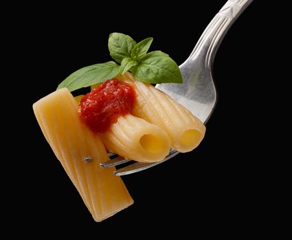 Pasta on the fork on the black background