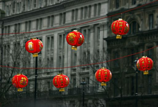 London, United Kingdom - February 18th, 2007: Seven red Chinese lanterns hanging on a rope with background of gray buildings during celebrations of Chinese new year in London