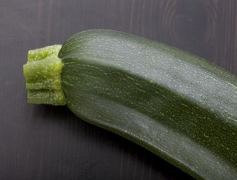 Top view of green zucchini piece on the black wooden table