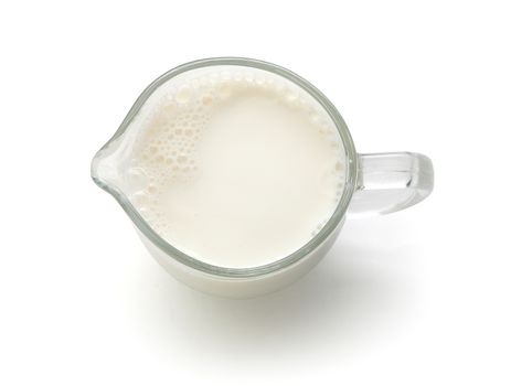 Top view of glass milk jug with milk on the white