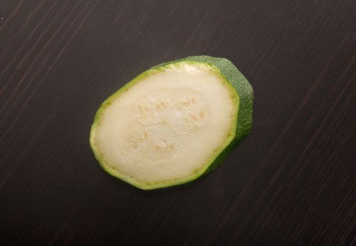 Top view of one green zucchini on the black wooden table