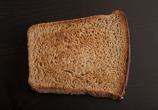 Top view of toasted rye bread on the black wooden table