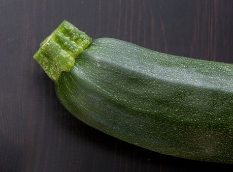 Top view of green zucchini piece on the black wooden table