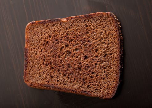 Top view of roasted rye bread on the black wooden table