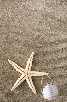 Medical protective mask and starfish on sand background