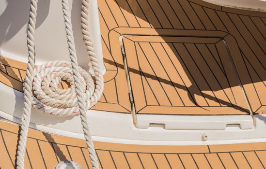 View of swirled curled rope bow on boat deck, nautical mooring line