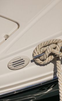 Close-up of nautical mooring rope is knotted on boat cleat