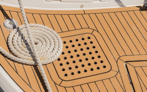 Close-up of curled mooring rope on boat deck at marina harbor