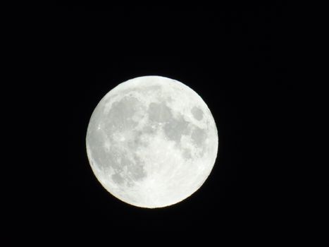 Genova, Italy - 07/05/2020: An amazing photography of the full moon over the city of Genova by night with a great clear and blue sky in the background and some stars.