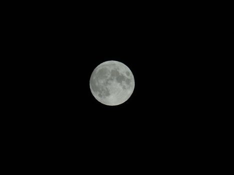 Genova, Italy - 07/05/2020: An amazing photography of the full moon over the city of Genova by night with a great clear and blue sky in the background and some stars.