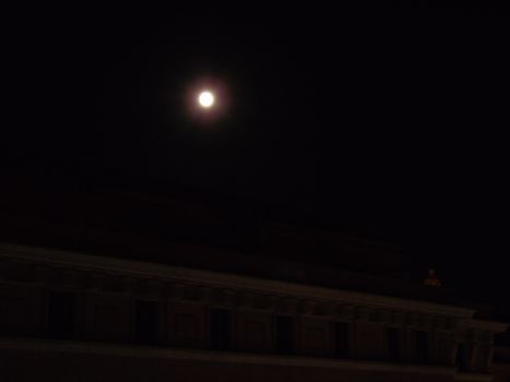 Genova, Italy - 07/05/2020: An amazing photography of the full moon over the city of Genova by night with a great clear and blue sky in the background and some stars.