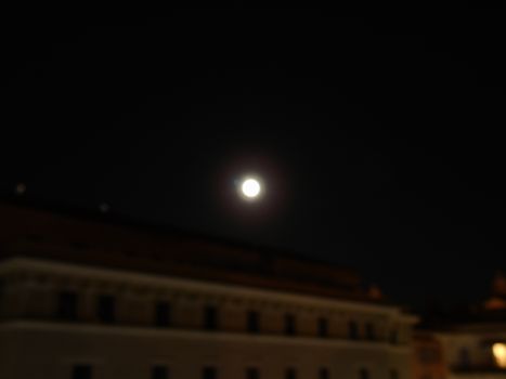 Genova, Italy - 07/05/2020: An amazing photography of the full moon over the city of Genova by night with a great clear and blue sky in the background and some stars.