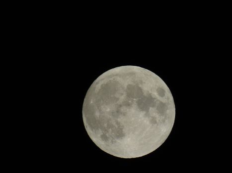 Genova, Italy - 07/05/2020: An amazing photography of the full moon over the city of Genova by night with a great clear and blue sky in the background and some stars.