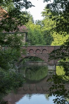 DE, Dortmund: June 2018: Bridge reflected in water at Haus Dellwig, Moated Castle in Westfalia
