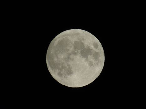 Genova, Italy - 07/05/2020: An amazing photography of the full moon over the city of Genova by night with a great clear and blue sky in the background and some stars.