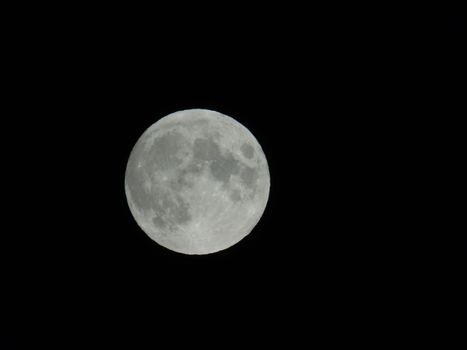 Genova, Italy - 07/05/2020: An amazing photography of the full moon over the city of Genova by night with a great clear and blue sky in the background and some stars.