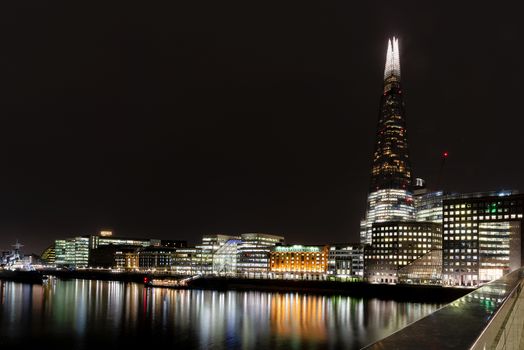 London, UK - Jan 2020: London, UK - Jan 2020: The Shard,  London Bridge Hospital, City Hall and other buildings on the South bank illuminated and reflecting in the Thames. Long exposure.