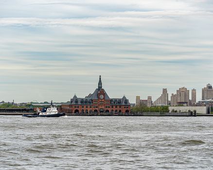 USA, New York - May 2019: Tug boat passing Central Railroad of New Jersey Terminal