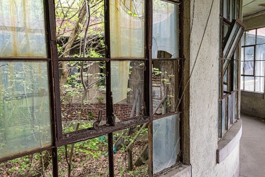 USA, New York, Ellis Island - May 2019:  Broken windows in the corridor of an abandoned hospital