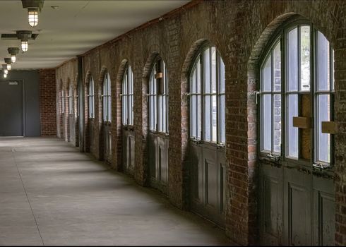 USA, New York, Ellis Island - May 2019: Long corridor walled with arched window panels