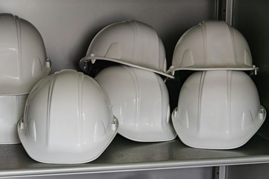 USA, New York, Ellis Island - May 2019: Shelf full of white hard hats  - focus on foreground left
