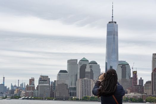 USA, New York, Ellis Island - May 2019: Unidentified woman photographing New York sky line