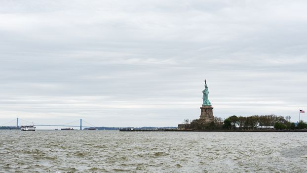 USA, New York, Ellis Island - May 2019: View of the Statue of Liberty & the Verrazzano-Narrows Bridge